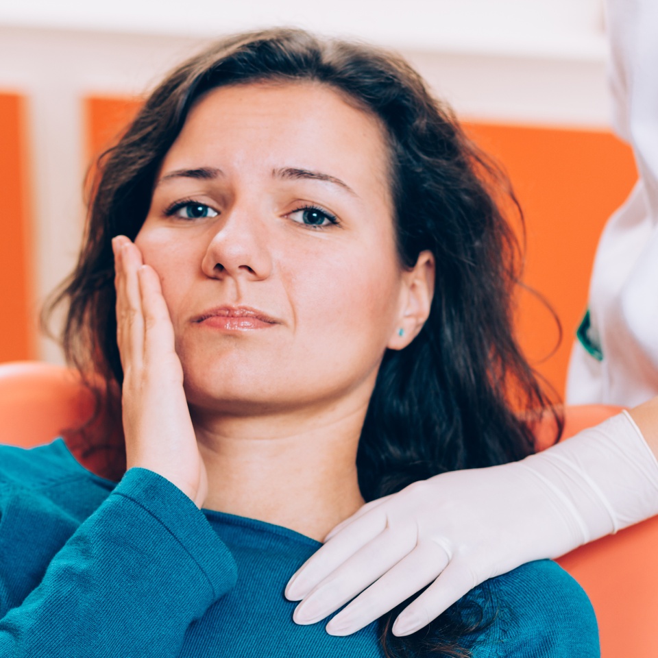 Upset woman having a toothache and holding hand on her cheek
