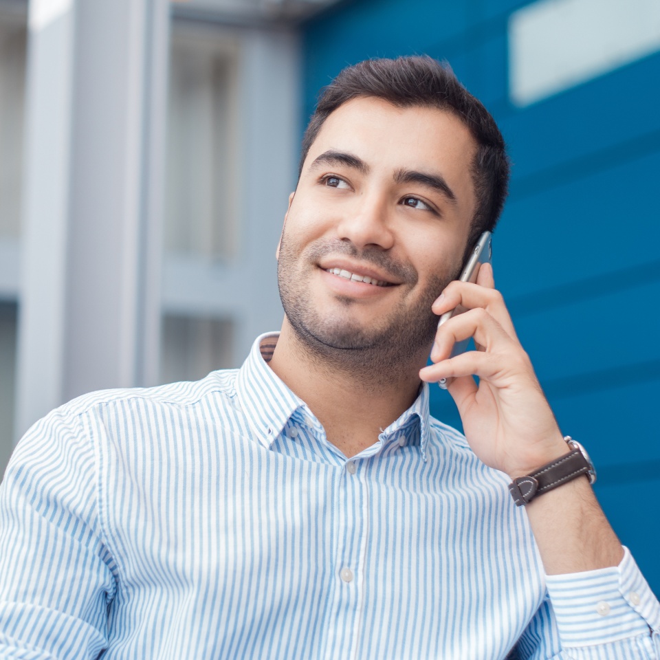 Happy young man on phone indoors - inside. Close up of businessman talking on mobile phone - smartphone. Comunicative friendly hispanic man