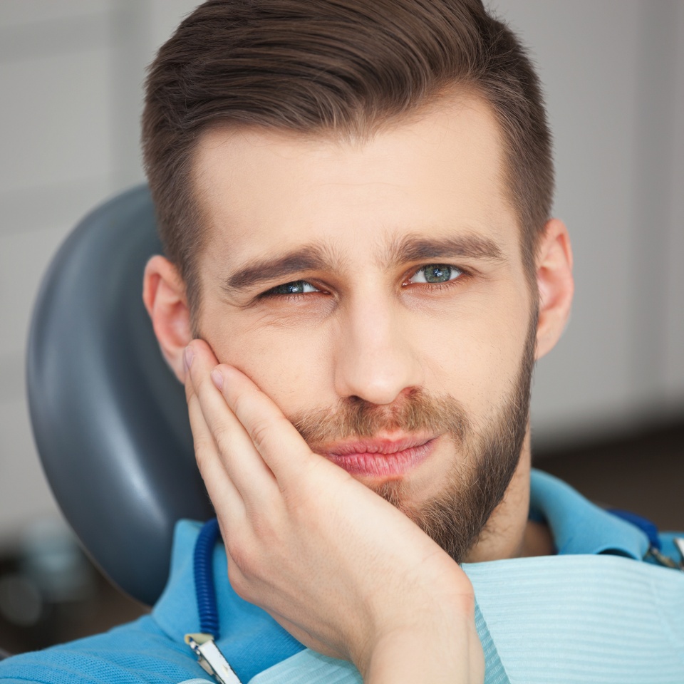 Shot of a young man with tooth pain while sitting in a dentist's chair.