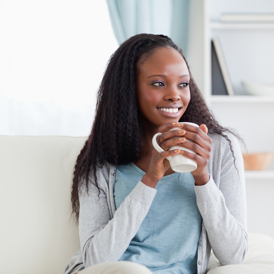 Smiling woman with a cup on couch