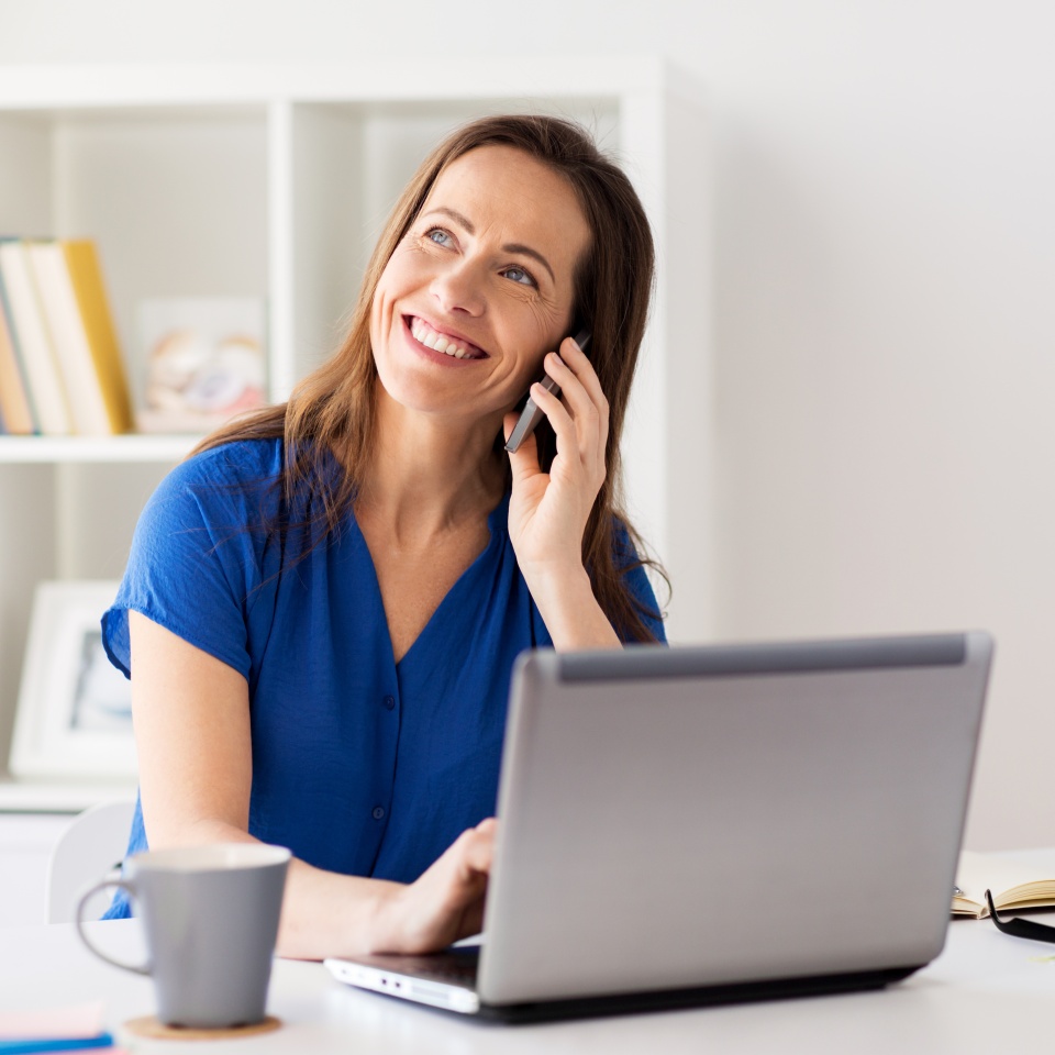 technology, communication and people concept - happy woman calling on smartphone at office or home