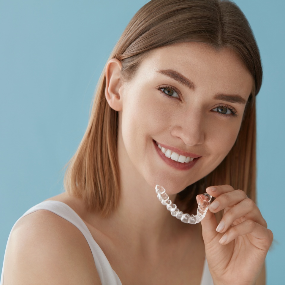 Teeth whitening. Woman with white smile, healthy straight teeth using clear removable braces, invisible teeth tray. Portrait of girl doing dental beauty treatment