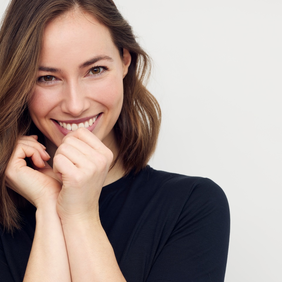 Portrait of beautiful young female or woman looking happy and confident in camera. Big smile on her face, looking beautiful standing isolated on white background. Concept: having a secret.