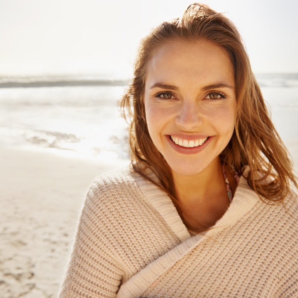 Travel, portrait and happy woman at a beach for summer, break or vacation, adventure or holiday. Ocean, face and female person smile at the sea with freedom, good mood or solo trip in South Africa