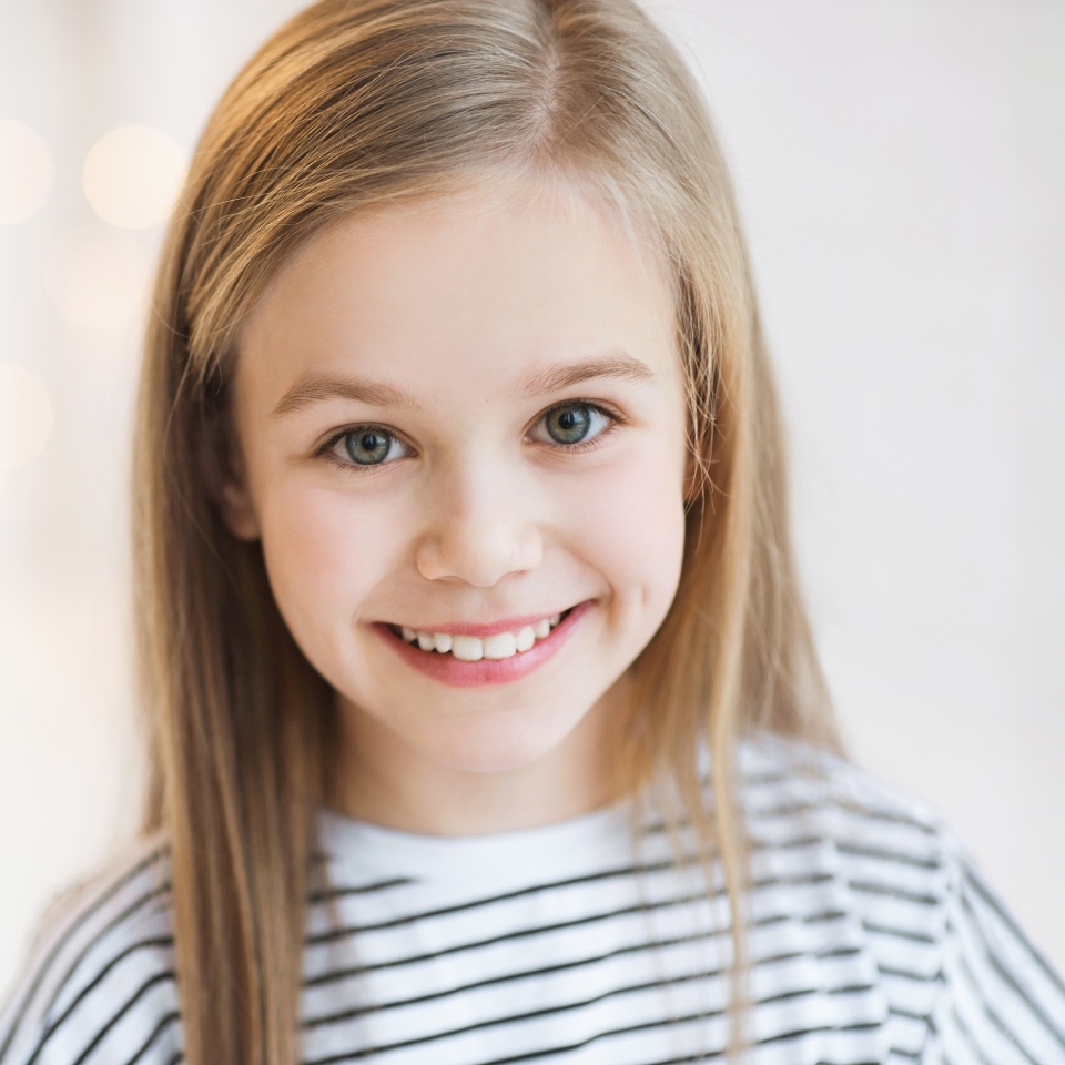 Cute little girl portrait at home. Funny child smiling and looking at camera