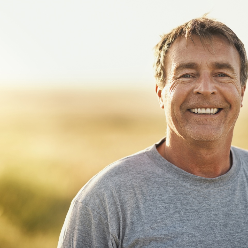 Senior man, smile and portrait at field in summer for outdoor adventure, nature and holiday. Sunshine, happy and face of person by mockup space for weekend vacation, peace and tourism in Turkey