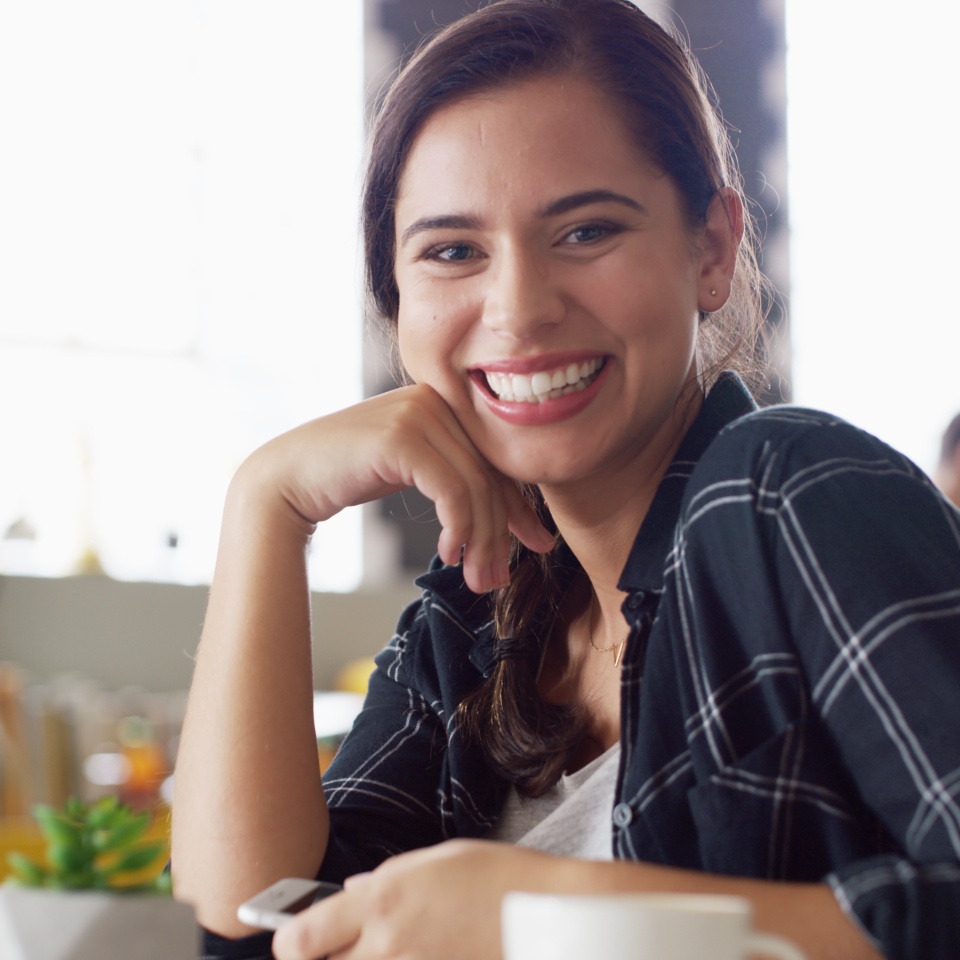 Portrait, smile and woman in coffee shop for relax, peace and calm on weekend break with phone. Face, cafeteria and confident customer in restaurant for service, hospitality and travel on holiday